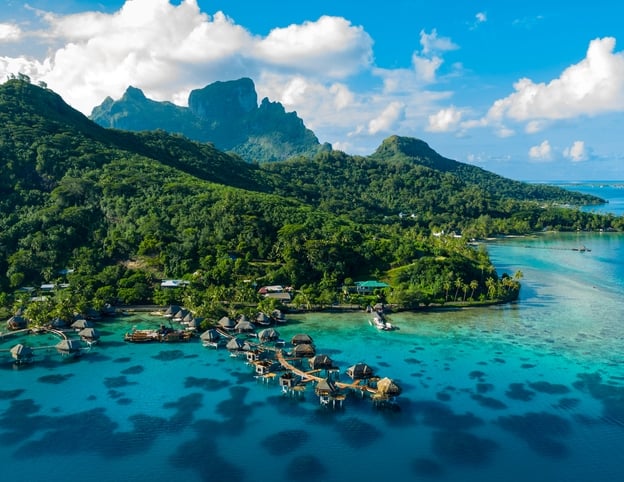 Bora Bora aerial drone video of travel vacation paradise with overwater bungalows luxury resort, coral reef lagoon ocean beach. Mount Otemanu, Bora Bora, French Polynesia, Tahiti, South Pacific Ocean