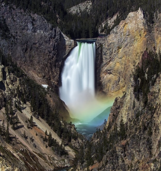 Lower Falls of the Yellowstone River at Yellowstone National Park. Early morning sunlight creates the conditions to form a rainbow at the base of the falls.