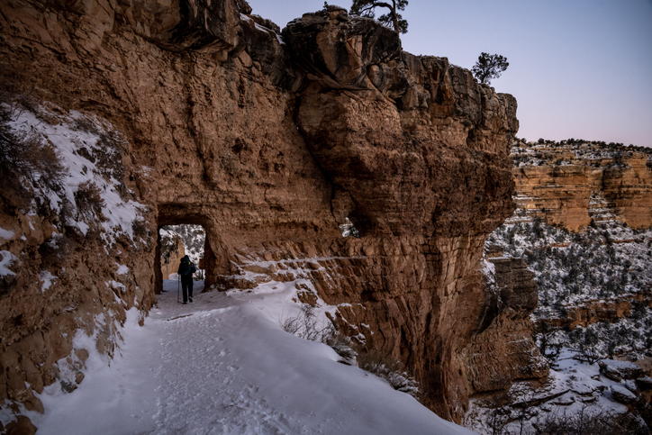 Hiker Passing Through Snow Covered Tunnel Along Bright Angel Trail in Grand Canyon National Park
