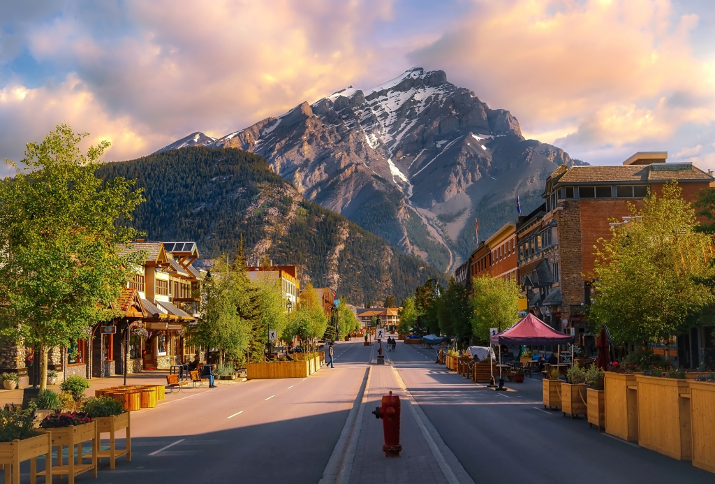 A colourful sunrise sky over a road leading through the town of Banff in the summertime.