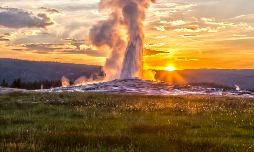 Old Faithful Geyser at Yellowstone National Park erupts at sunset.