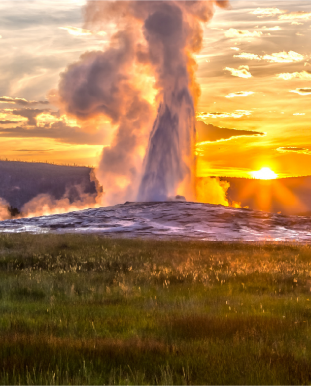 Old Faithful Geyser at Yellowstone National Park erupts at sunset.