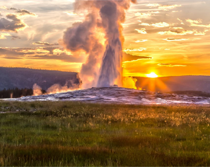 Old Faithful Geyser at Yellowstone National Park erupts at sunset.