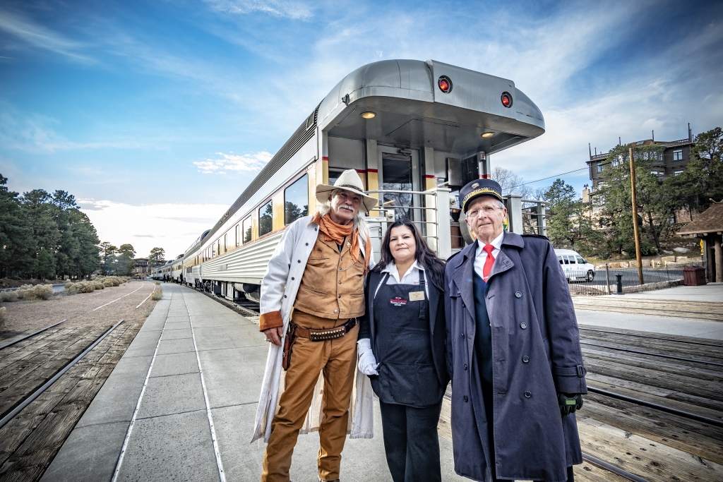 Three people stand in front of a train