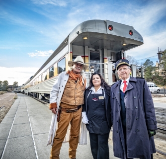Three people stand in front of a train