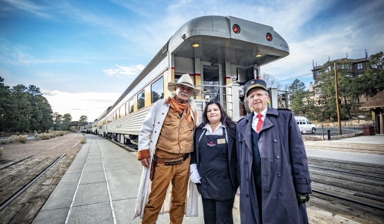 Three people stand in front of a train