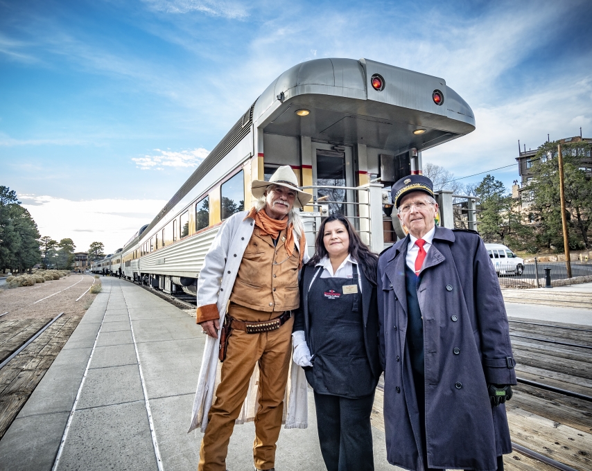 Three people stand in front of a train