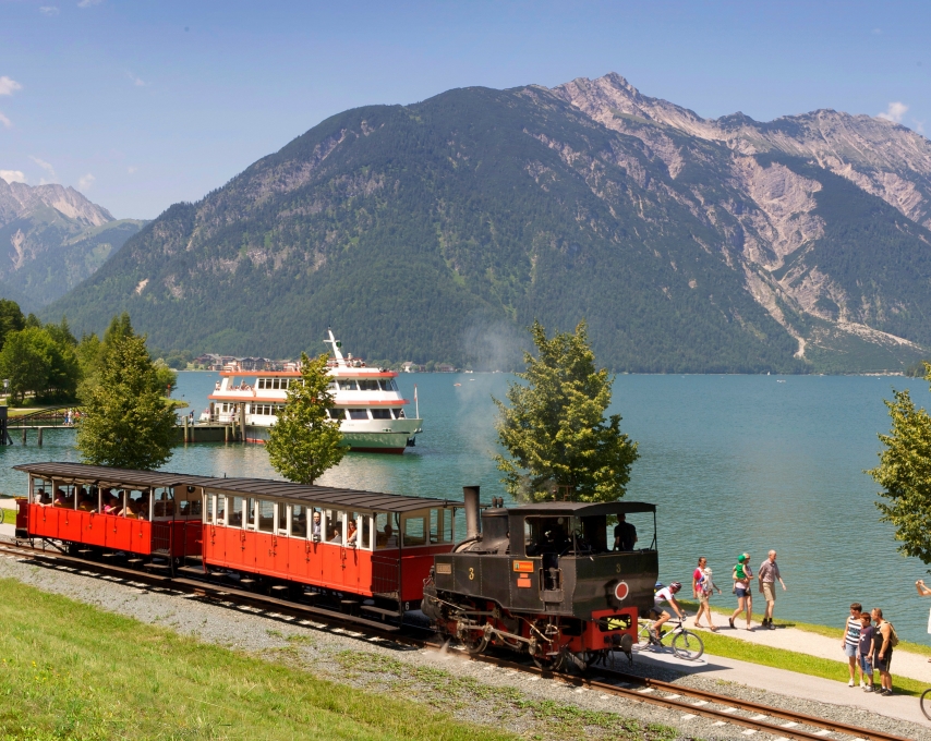tourist train by the water and mountain