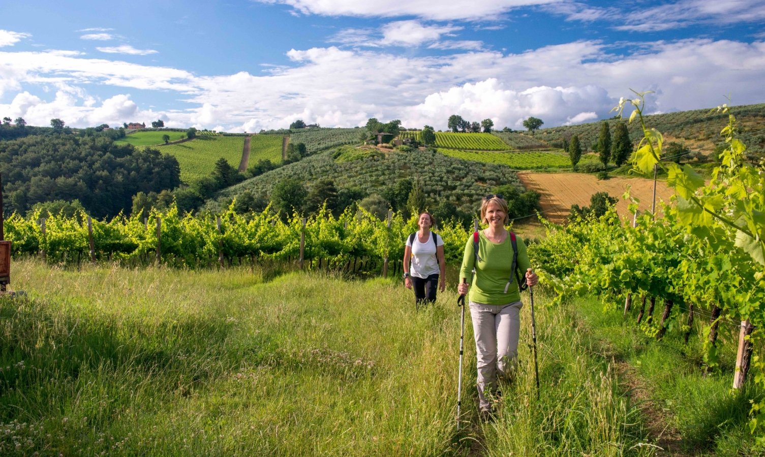 Two women walking through a green landscape