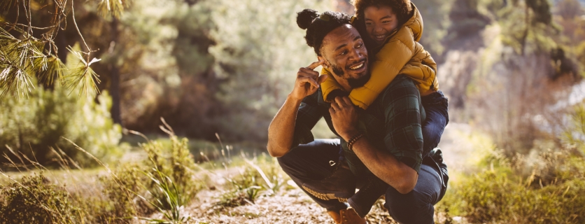 Dad and son bonding and having fun with piggyback ride on mountain hiking adventure
