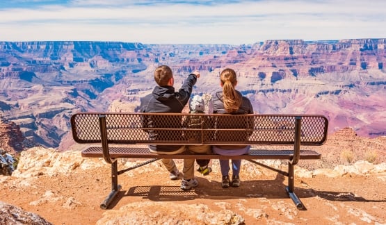 Stock photograph of a family with one child looking at view in Grand Canyon National Park, South Rim, USA on a sunny day.