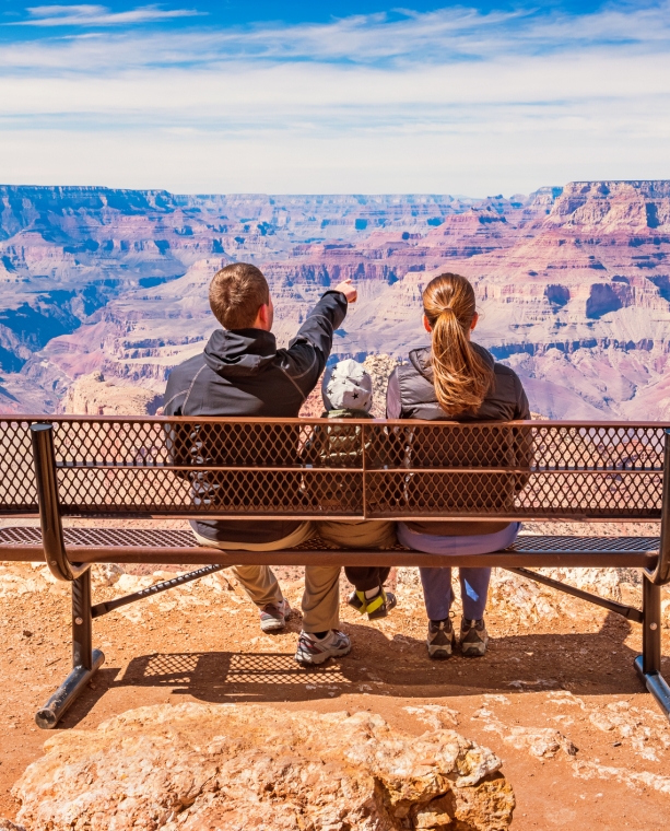 Stock photograph of a family with one child looking at view in Grand Canyon National Park, South Rim, USA on a sunny day.