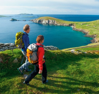 Hikers walk across a green landscape