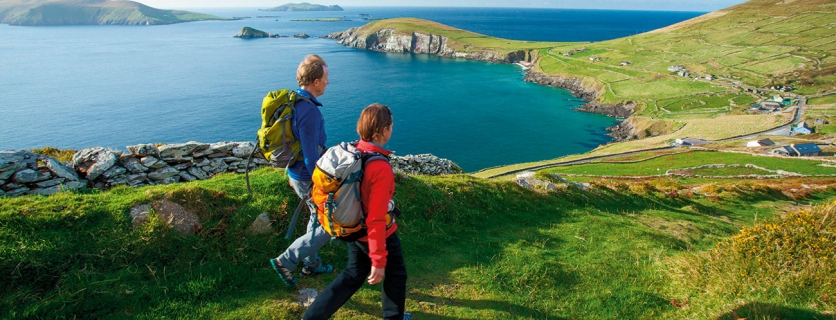 Hikers walk across a green landscape