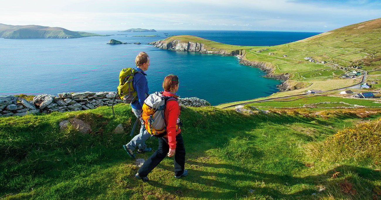 Hikers walk across a green landscape