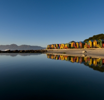 St James beach , Cape Town. Colorful bathing huts reflecting in tidal pool at sunrise