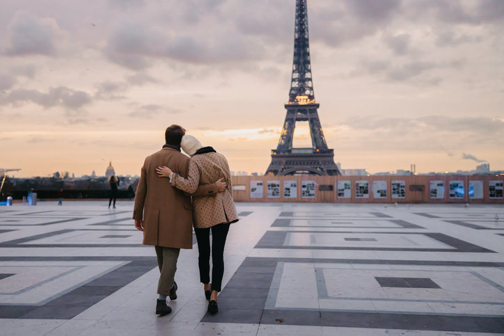 Couple hugging each other and leaning their heads at each other while walking on Parvis des Droits de l'Homme in the direction of Eiffel Tower Paris, rear view, evening with beautiful sky, horizontal