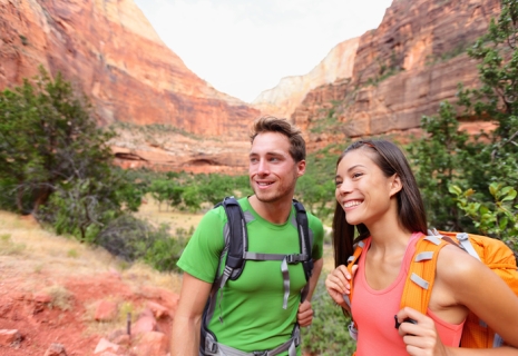 Hiking people - hiker couple on hike outdoors enjoying active lifestyle in beautiful mountain landscape in Zion National Park. Multiracial Asian woman and Caucasian man in Utah, USA.