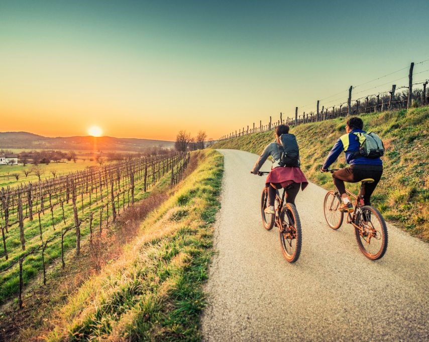 Biker couple riding moutain bike in the countryside at sunset